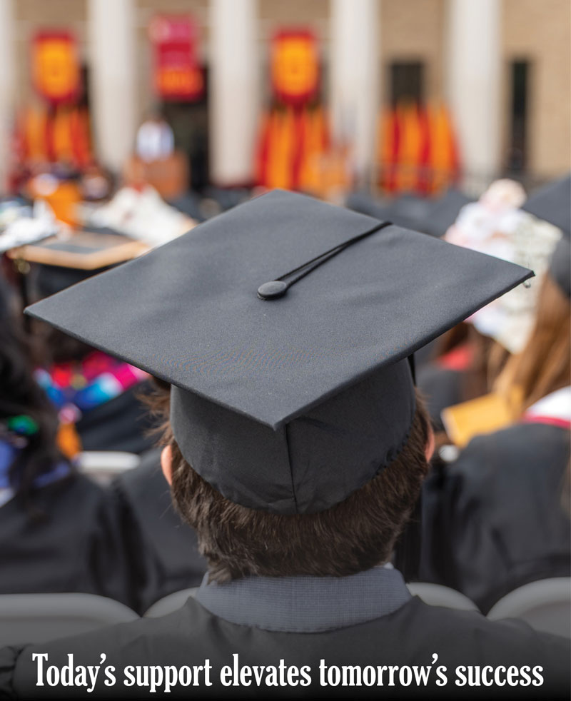 Graduating senior at Commencement facing the stage with white text at the bottom that reads "Today's support elevates tomorrow's success"