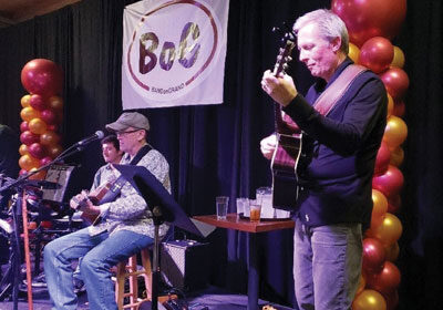 President Steven O'Day playing an acoustic guitar on stage