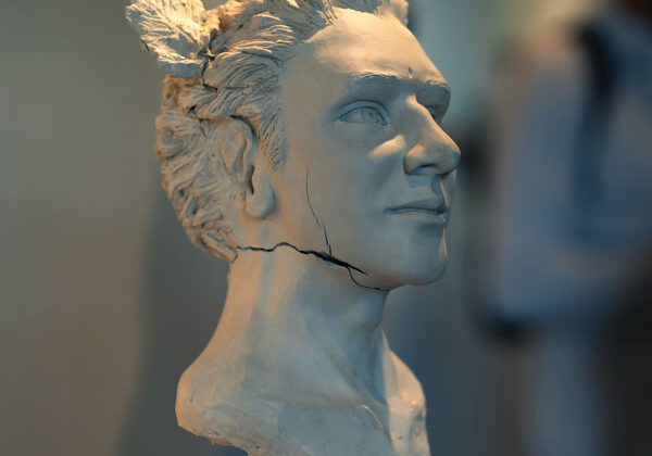 Off-white Sculpture of person with short hair and cracks under the jaw past the ear